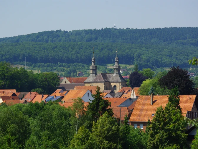 Blick auf das Kloster Willebadessen umgeben von roten Dächern und grüner bewaldeter Hügellandschaft.