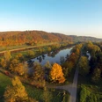 Weserhöhen_Weserradweg_Wehrden Herbstliche Luftaufnahme des Weserradwegs bei Wehrden, eingerahmt von einem von Laubbäumen gesäumten Fluss.