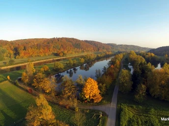 Weserhöhen_Weserradweg_Wehrden Herbstliche Luftaufnahme des Weserradwegs bei Wehrden, eingerahmt von einem von Laubbäumen gesäumten Fluss.