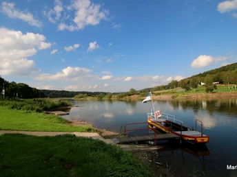 Weserhöhen_Fährstelle_Wehrden Fährstelle an der Weser mit ruhig fließendem Fluss, grünem Uferbereich und bewaldeten Hügeln.