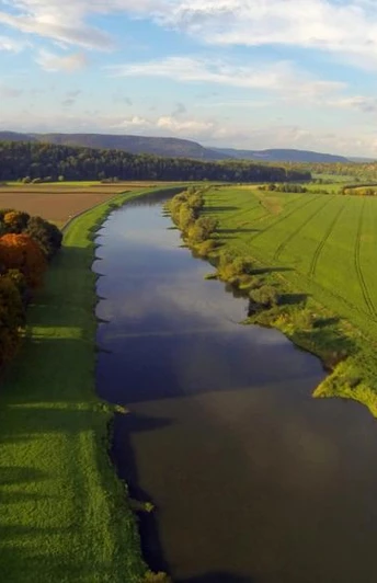 Weserhöhen_Weserpartie_Wehrden_oben_links_Bosseborner_Höhen Luftaufnahme der Weserflussschleife bei Wehrden mit grünen Feldern und dichten, bunten Baumreihen.