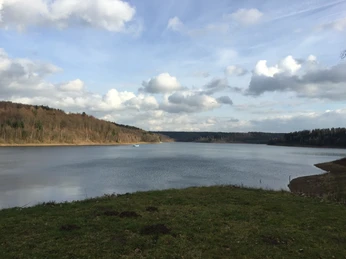 Aabachtalsperre Bad Wünnenberg Aabachtalsperre bei Bad Wünnenberg mit ruhigem Wasser, umgeben von bewaldeten Hügeln unter Wolkenhimmel.