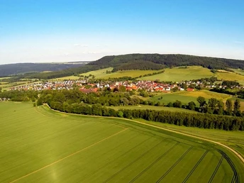 Blick auf Amelunxen im Nethetal Luftaufnahme von Amelunxen, einem Dorf umgeben von grünen Feldern und sanften Hügeln im Nethetal.