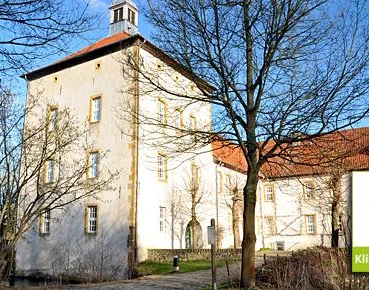 Gut Bustedt Historisches Gut Bustedt mit gelber Fassade und Turm im Vordergrund, Bäume im Winterkleid.