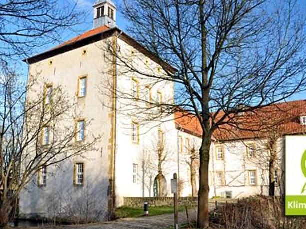 Gut Bustedt Historisches Gut Bustedt mit gelber Fassade und Turm im Vordergrund, Bäume im Winterkleid.