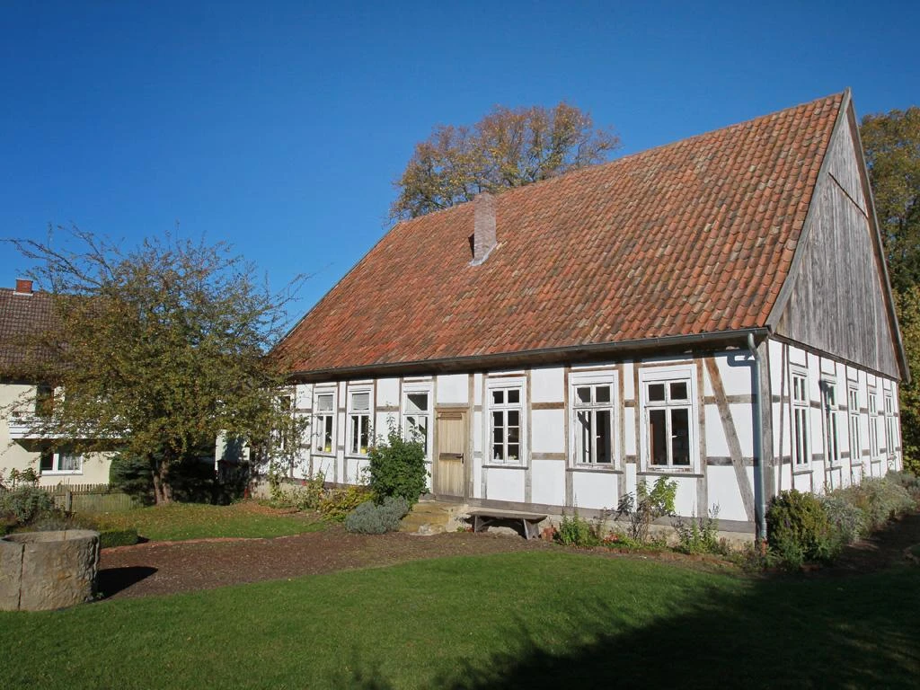 Museumsschule Hiddenhausen Ein historisches Fachwerkgebäude mit blumengeschmücktem Garten und roten Dachziegeln bei Sonnenlicht.
