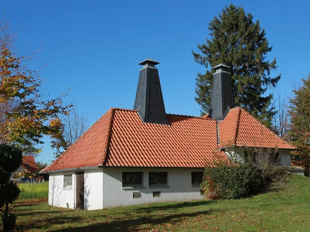 Ältestes Wasserwerk im Kreis Herford Das älteste Wasserwerk im Kreis Herford, rot gedecktes Dach, markante Schornsteine, umgeben von Grün.