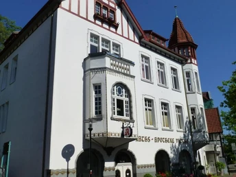 Historisches Gebäude mit Fachwerk- und Backsteinelementen, verziert mit Apotheke-Schild im Vordergrund.