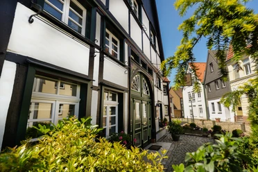 Innenstadt Lünen Fachwerkhäuser in der Altstadt von Lünen bei sonnigem Wetter, umgeben von grüner Vegetation.