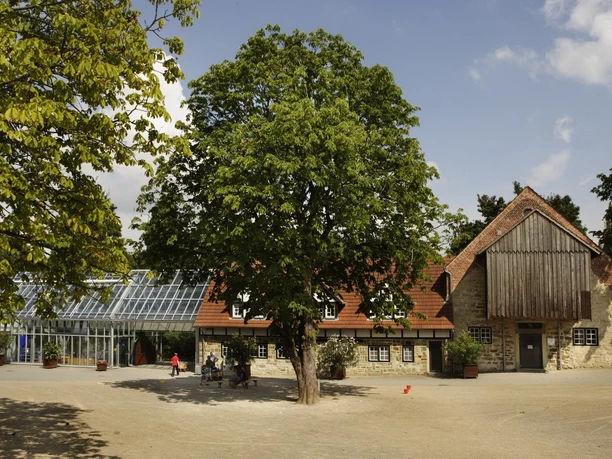 Kindermuseum Klipp Klapp im Vier-Jahreszeiten-Park Ein traditionelles Fachwerkgebäude neben einem modernen Glashaus im Vier-Jahreszeiten-Park.