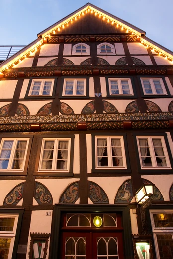Ratskeller Fachwerkhaus in traditionellem Stil, mit beleuchtetem Giebel und dekorativen Fassadenmalereien.