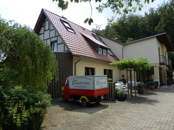 Außenansicht, Landgasthof Mücke in Marsberg Ein zweigeschossiger Landgasthof mit rotem Satteldach und Fachwerkelementen, umgeben von Bäumen.