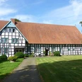 Hof Oberwahrenbrock Fachwerkhaus auf gepflegtem Rasen, Hof Oberwahrenbrock, mit großen Dach und weiß-schwarzen Strukturen.