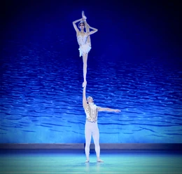 An acrobatic duo in white at the Cologne Christmas Circus in front of a blue-lit stage