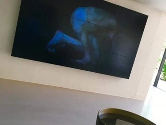 Ein großer Bildschirm zeigt abstrakte Kunst auf einer glatten, modernen weißen Wand.