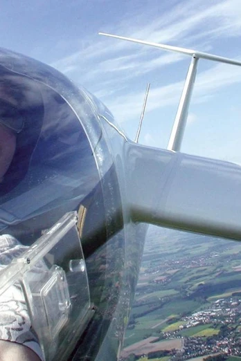 Segelflieger über Oerlinghausen Person in einem Segelflugzeug, fotografiert aus der Pilotenkabine, überblickt Felder und Landschaften.
