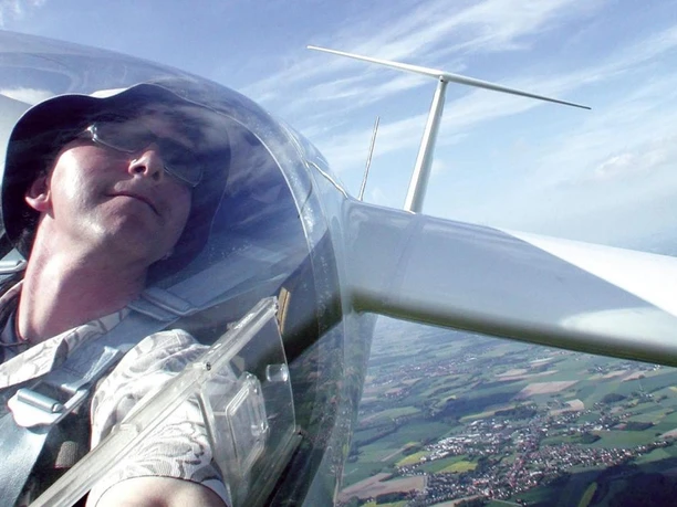 Segelflieger über Oerlinghausen Person in einem Segelflugzeug, fotografiert aus der Pilotenkabine, überblickt Felder und Landschaften.