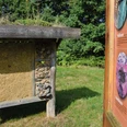 Insektenhotel mit informativer Schautafel Insektenhotel mit natürlichen Baumaterialien, flankiert von einer Schautafel zur Insektenwelt.