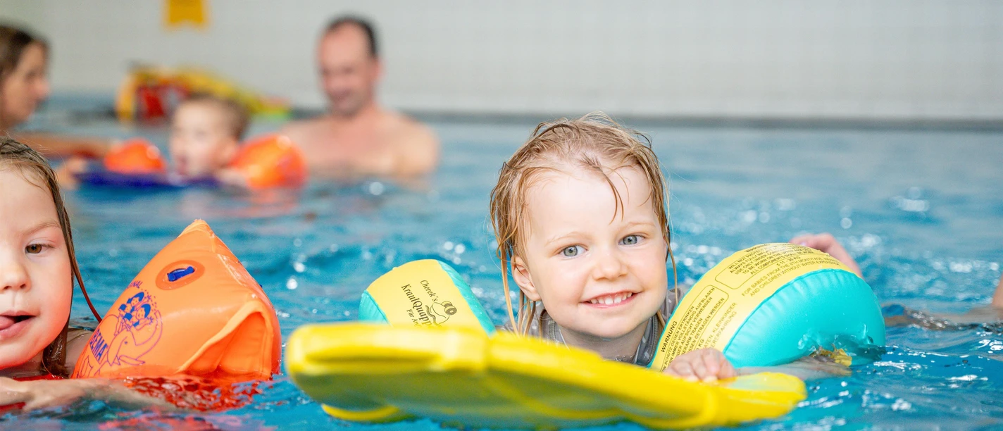 Kind mit Schwimmflügeln und Schwimmbrett