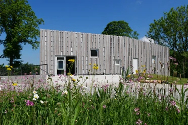 Besucherzentrum Marienmünster Das Besucherzentrum Marienmünster mit moderner Holzfassade, umgeben von bunten Wildblumen.