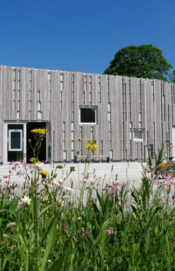 Besucherzentrum Marienmünster Das Besucherzentrum Marienmünster mit moderner Holzfassade, umgeben von bunten Wildblumen.