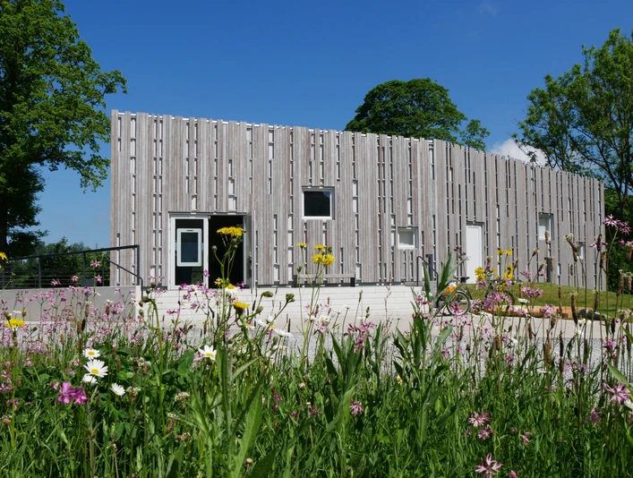 Besucherzentrum Marienmünster Das Besucherzentrum Marienmünster mit moderner Holzfassade, umgeben von bunten Wildblumen.