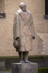 Konrad Adenauer Monument in Cologne: a bronze figure wearing a coat and hat, standing in front of a stone wall