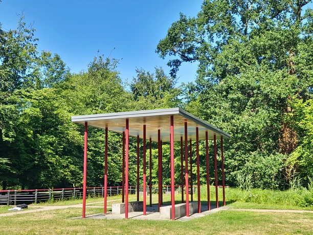 Moderner Pavillon mit roten Säulen und flachem Dach auf der Dalkeinsel in Gütersloh.