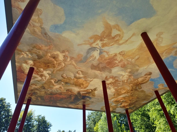 Deckenfresko mit mythologischen Gestalten, getragen von roten Säulen im Park.