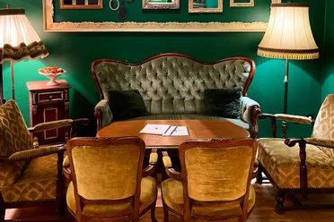 Café & Bistro Wunderland: Grüner Gastraum mit Samtsofa, gelben Sesseln und Wandrahmen.
