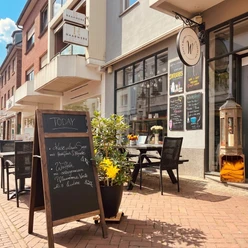 Außenbereich des Café & Bistro Wunderland mit Tischen, Stühlen und einer Menütafel.