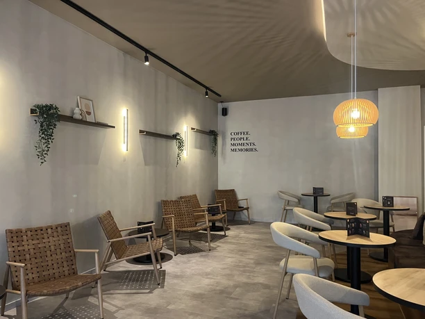 Moderner Gastraum des Zerino Coffee mit hellen Holzmöbeln, runden Tischen und grauen Wänden.