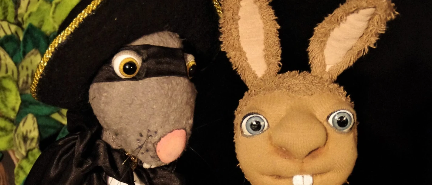 Raeuber Ratte Zwei Handpuppen stehen nebeneinander: eine als Räuber verkleidete Figur und ein Hase mit kariertem Latz.