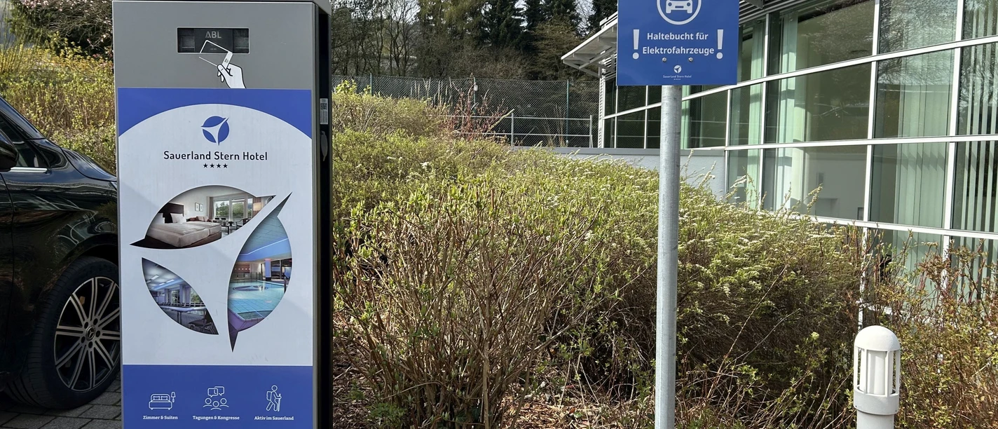 E-Ladesäule am Sauerland Stern Hotel mit Hinweisschild und parkendem Auto