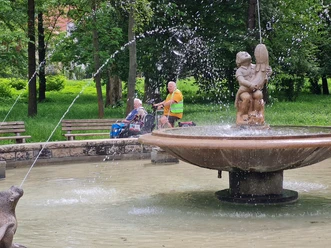 Brunnen in der Oberaue Jena, dahinter fährt eine Fahrradrikscha