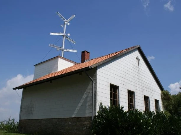 Oeynhausen, Telegrafenstation Weißes Gebäude mit kleinem Kirchturm und Telegrafenstation auf dem Dach unter strahlend blauem Himmel.