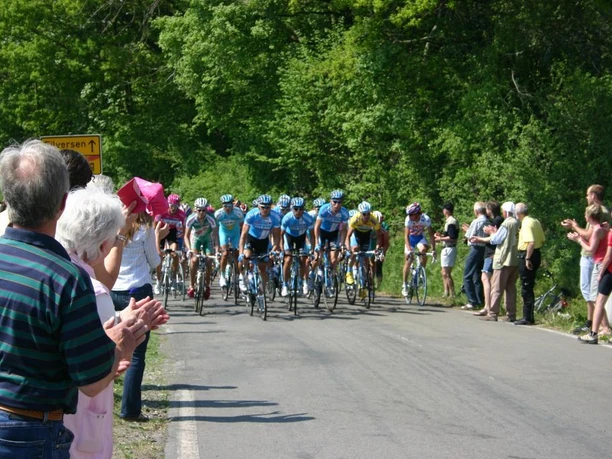 Vörden, Radrennen Radfahrer in einem Wettkampf auf einer ländlichen Straße, gesäumt von applaudierenden Zuschauern.