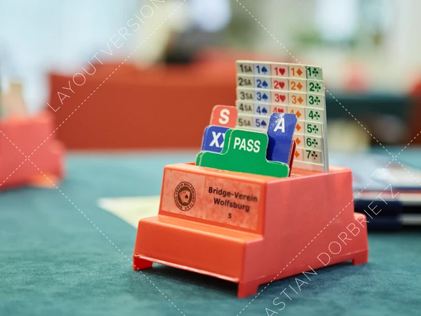 Bridge.jpg Ein roter Bridge-Halter steht auf einem Spieltisch.