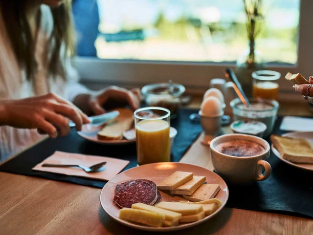 Breakfast at Z Reschti by the window, with sausage, cheese, eggs, coffee, and orange juice