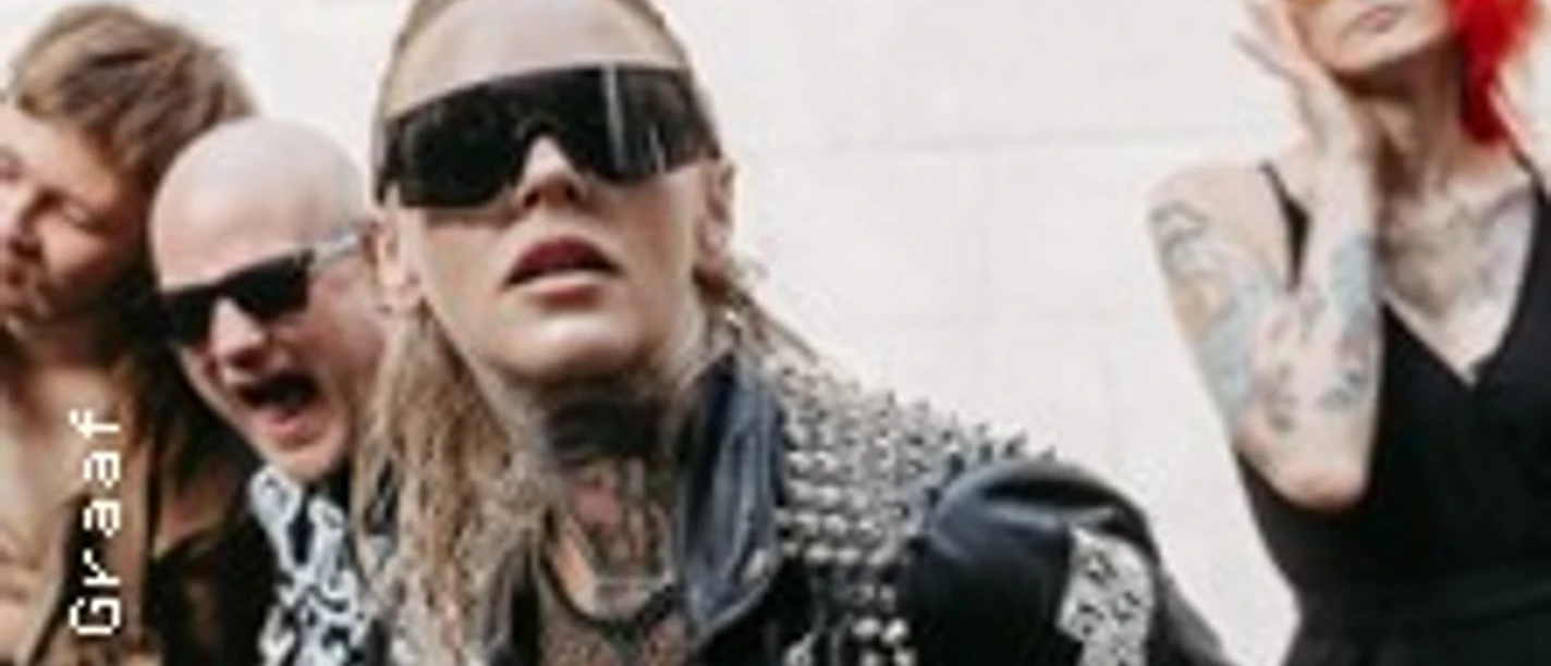 Vier Punkrock-Musiker posieren vor heller Wand, mit Sonnenbrillen, Tattoos und Lederjacken