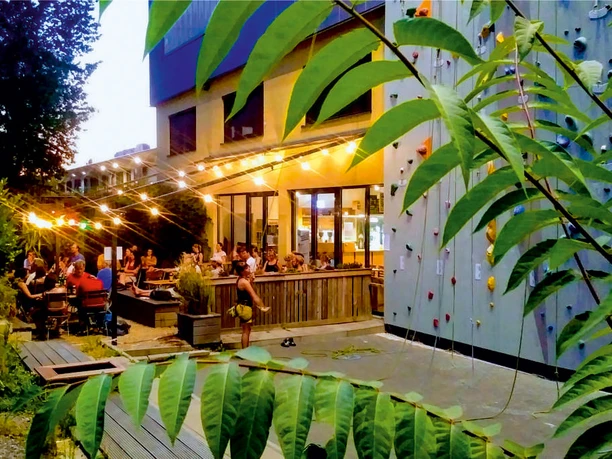 CheckIn und Bar-Cafe in der Kletterfabrik Köln Außenbereich der Kletterfabrik Köln mit beleuchteter Terrasse und Kletterwand am Abend