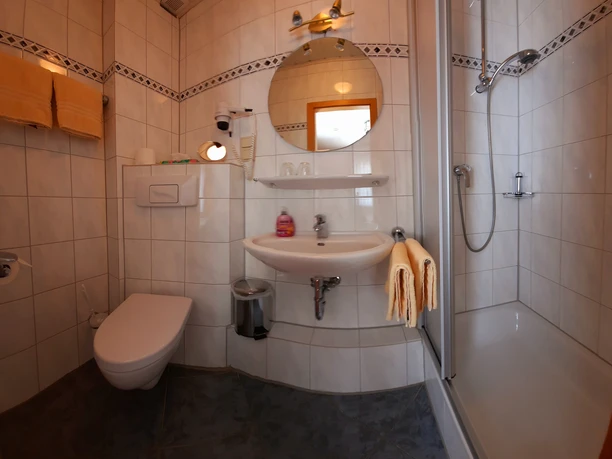 Schäferhaus Willingen, Badezimmer Helles Badezimmer mit Dusche, WC, Waschbecken, Rundspiegel und gelben Handtüchern