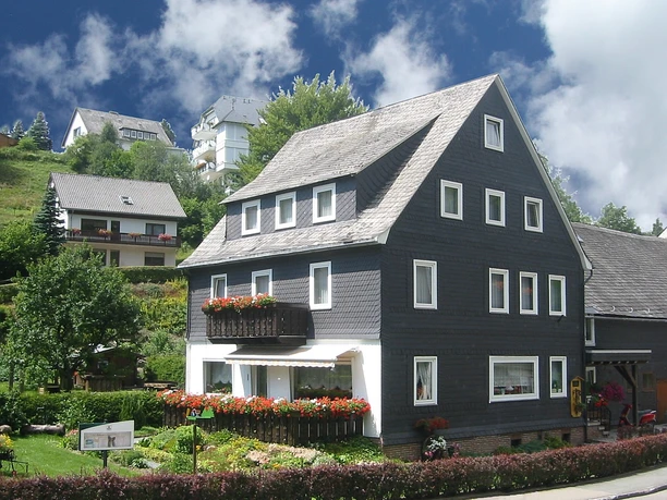 Schäferhaus Willingen, Ansicht Schieferverkleidetes Ferienhaus mit Balkonen, Blumenkästen und Garten in Hanglage