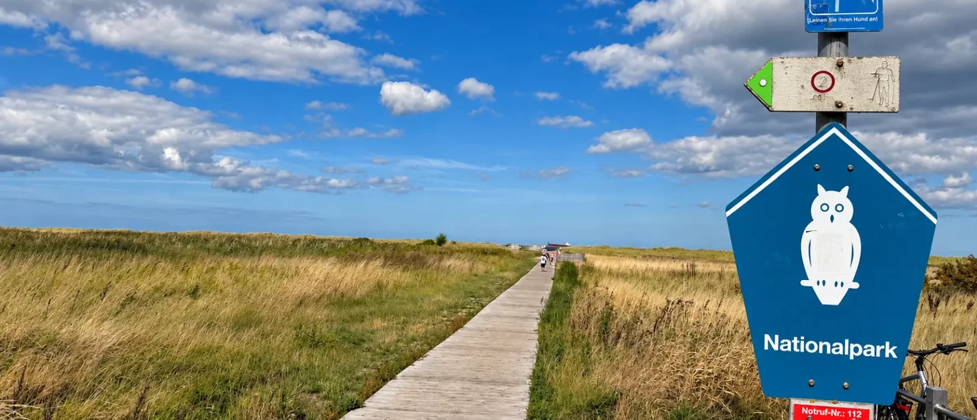 Nationalpark-Schild am Strandweg in Schillig mit Bohlenweg und Fahrrad