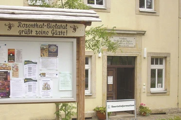 Hauswand mit Tür, im Vordergrund Infotafel; Ort Rosenthal-Bielatal