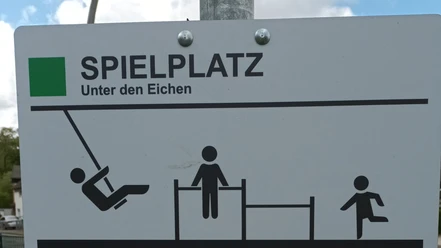 Schild „Spielplatz Unter den Eichen“ mit Piktogrammen für Schaukel und Spielgeräte.