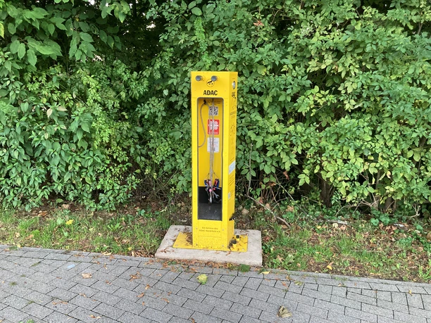 Radservice-Station in Bechen Gelbe ADAC-Radservice-Station mit Werkzeug und Luftpumpe vor dichtem Grün am Gehweg