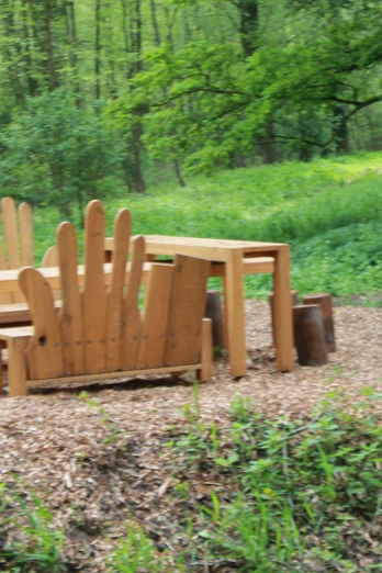Rastplatz "Fühlen" Holztisch und Stühle im Freien, umgeben von üppigem Grün und Bäumen auf Waldboden.