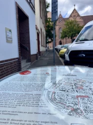 Infofass zum Einbecker Bierpfad, im Hintergrund eine historische Backsteinkirche.