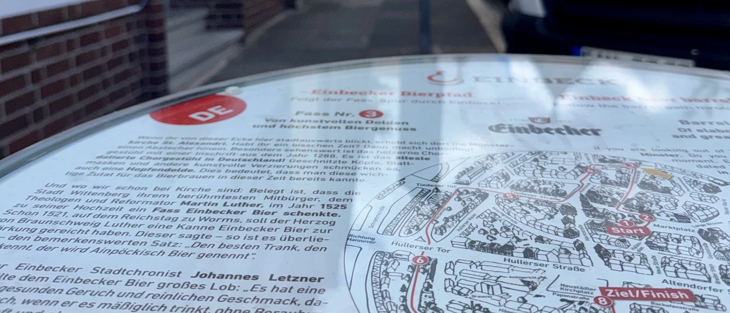 Information sign for the Einbeck Beer Trail, with a historic brick church in the background.